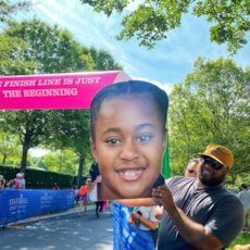 Supporter smiling while holding giant poster of a GOTR Participant's face